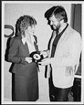 Larry Mercey handing a record to a woman [entre 1980-1990].