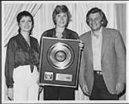 Anne Murray receiving a platinum award for her album "Let's Keep It That Way" with Nancy Engler (left, Entertainment Director, Aladdin Hotel) and Don Zimmerman (President and Chief Operating Officer, Capitol-EMI Records) at the Aladdin Hotel, Las Vegas [entre 1978-1979].