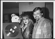 Stevie Nicks holding a stuffed animal and an award for her album 1989