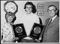 Alice Koury and F.C. Jamieson of London Records, stand beside Producer, Jurgen Korduletsch, who holds up two Gold records for the singles, "Soul Sister" and "Why Must A Girl Like Me" [entre 1977-1979].