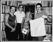 WEA's Wolf Burant and Miss Vancouver Bikini, with Jane Siberry's single "Mimi On The Beach", at the office of FM 97 [ca. 1984].
