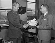 Major-General Geoffrey Walsh, left, Quartermaster-General of the Army presented two cheques and a Suggestion Award Certificate to Henry H. Slack 15 December 1958.