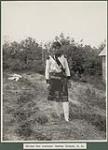 Mi'kmaq man [J. Paul] standing in a grassy clearing wearing war regalia, Indian Island, Nova Scotia July 10, 1914.