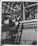 A parachute flare, used to illuminate a U-boat spotted at night by Sunderland flying boats of Coastal Command, is handed to P/O R.A. Stubbs by F/O D.E. Cameron 5 February 1944.
