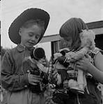 Children examine Mrs. Betsy Howard's dolls outside her roadside workshop July 1956.