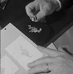 Examen d'une broche ornée de diamants et de perles à l'aide d'une loupe 1956