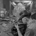 Henri Hernandez ajoute des décorations sur une couronne 1957