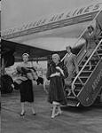 Des mannequins et agentes de bord descendant d'un avion à Paris 1957