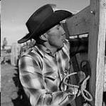 Un homme [George Good Striker] de la tribu des Gens-du-Sang calmant son cheval 1958