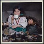 [Sheouak Petaulassie drinking from a mug with her son, Cape Dorset, Nunavut] 1962