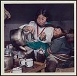 [Sheouak Petaulassie pouring water from a kettle into a mug, Cape Dorset, Nunavut] April 17, 1962