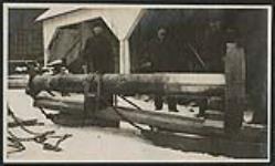 [Men standing with old machinery at Mill] 1910