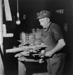 Workman Joe Martin operates a vice in preparation for routing the wooden stock of a .22 calibre training rifle in the H.W. Cooey Co. Ltd. munitions plant mai 1944