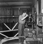 Workman Jack Elliot drills the butt of a .22 calibre training rifle before installation of fittings at the H.W. Cooey Company Ltd. munitions plant May 1944