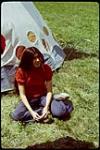 [First Nations woman sitting by a tipi] July 1972