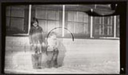 [Two Inuit children standing outside by windows] [between 1900-1950]