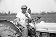[Councillor Cedrick Marable, Kanien'keha:ka (Mohawk) from Tyendinaga, sitting on a tractor and smoking a cigarette] [ca. 1959]