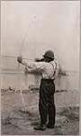 [Rear view of Anishinaabe man, Michel Finlayson, drawing a bow and arrow] [ca. 1916]