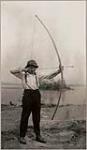 [Front view of Anishinaabe man, Michel Finlayson, drawing a bow and arrow] [ca. 1916]