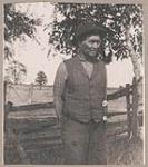 [First Nations man standing outside by a fence] 1912