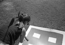 Woman painting a sign laid on the grass 29 August 1990