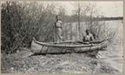 [Two women with birch bark canoe at shore] [between 1910-1921]