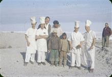 [Work camp cooks and two unidentified men with three Inuit boys] 1956