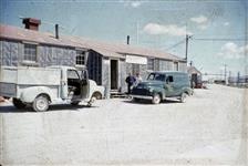 [Two men with pickup trucks outside of a Deli store] 1956