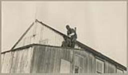 [Unidentified men on top of a roof, one man is cutting the other man's hair] [between 1921-1922]
