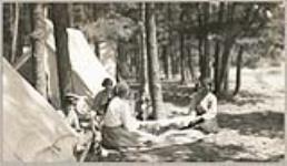 [Anishinaabe women stretching a deerskin as children watch] 1919