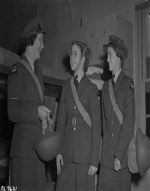 Metal millinery or what the well-dressed airwoman wears for duty at a RCAF operational base "somewhere in New-founding." The helmet is modelled by Airwoman First Class F.M. Thompson of Montreal for Leading Airwoman M.H. Robin, of Roblin, Man., (LEFT) and AW1 K.V. Reed of Toronto (RIGHT) [between 1940 and 1965]