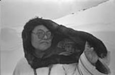 [Portrait of Komoratuk Mathewsie outside carrying a baby in an amauti] December 1980