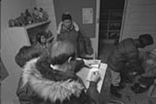[People buying and selling Inuit sculptures at West Baffin Cooperative, Cape Dorset (Kinngait)] November 1980