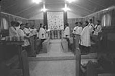 [Oshoochiak Pudlat and other choir members singing at St. John Anglican Church, Cape Dorset (Kinngait)] November 1980