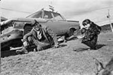 [Two people,Lawrence Paul and Cindy Paul, sit by a car, Mi'kmaq Reserve, Millbrook] [ca. 1969].