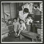 In a Lemon Creek home a Japanese mother puts a bib on one of her children [1945/06/16-1945/06/28]