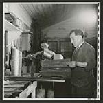In the tinsmith shop at Tashme stove pipes and other plumbing necessities are made for evacuee houses [1945/06/16-1945/06/28]