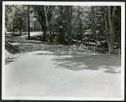 [Chained-off section of road under construction in Rockcliffe, sourrounded by woods] [1927-1932].