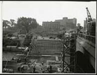 [View of workers widening the Plaza Bridge and constructing the driveway along the Rideau Canal, looking west towards Elgin Street] August 31, 1938