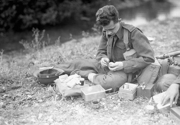 An unidentified member of the Royal Canadian Army Medical Corps (R.C.A.M.C.) conducting field trials of mess tins and emergency rations, Penobsquis, New Brunswick, Canada, ca. 2-11 September 1942.