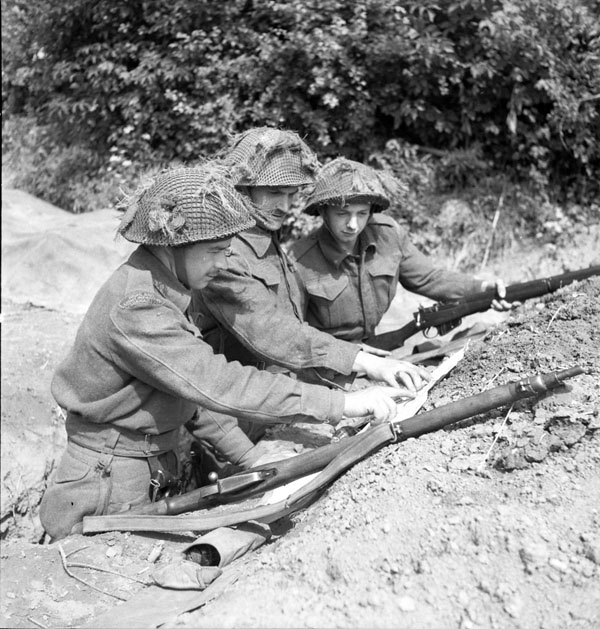 Platoon commander Lieutenant J.H. Chrystler (centre) issuing patrol instructions to Sergeant F.C. Edminston and Private L.J.L. Coté, all of The Highland Light Infantry of Canada, France, 20 June 1944.