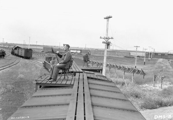 An unidentified Bren gunner sitting atop one of the cars of No.1 Armoured Train at Canadian National Railways Transcona Shops, Winnipeg, Manitoba, Canada, 15 July 1942.