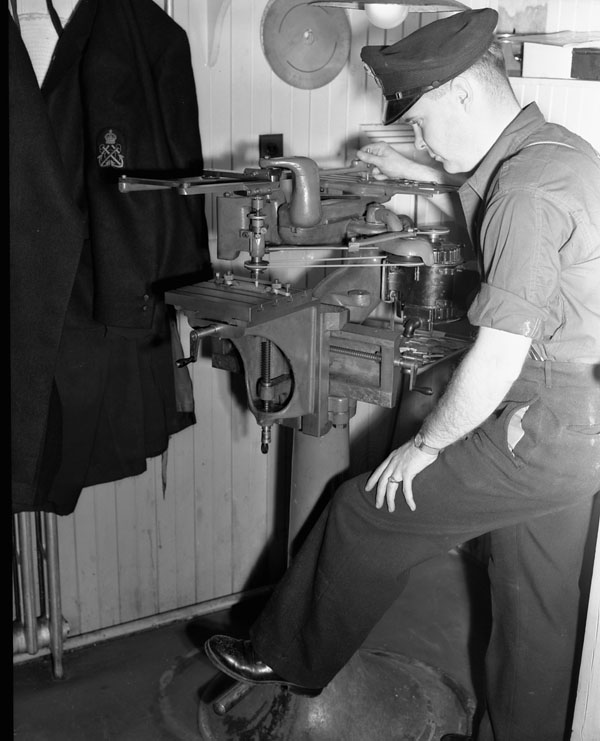 A Chief Electrical Artificer operating a power drill in the Electrical Artificers' Workshop, H.M.C. Dockyard, Halifax, Nova Scotia, Canada, 18 November 1942.