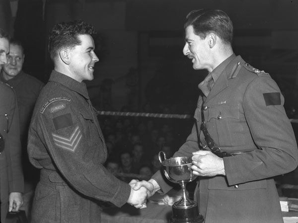 Brigadier J.D.B. Smith (right) presenting a boxing trophy to Sergeant George Nyberg of the Lake Superior Regiment. England, 21 January 1944.