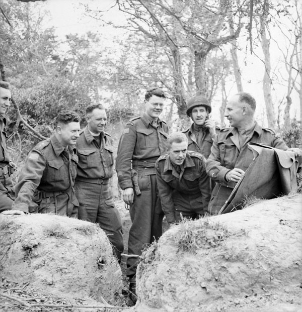 Lieutenant-Colonel P.C. Klaehn (centre), Commanding Officer of The Cameron Highlanders of Ottawa (M.G.), holding a map session with officers of the regiment near Caen, France, 15 July 1944.