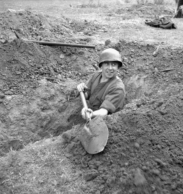 Sgt. Al Grayston, Canadian Film and Photo Unit, digging a trench, Normandy, France, 10 June 1944.