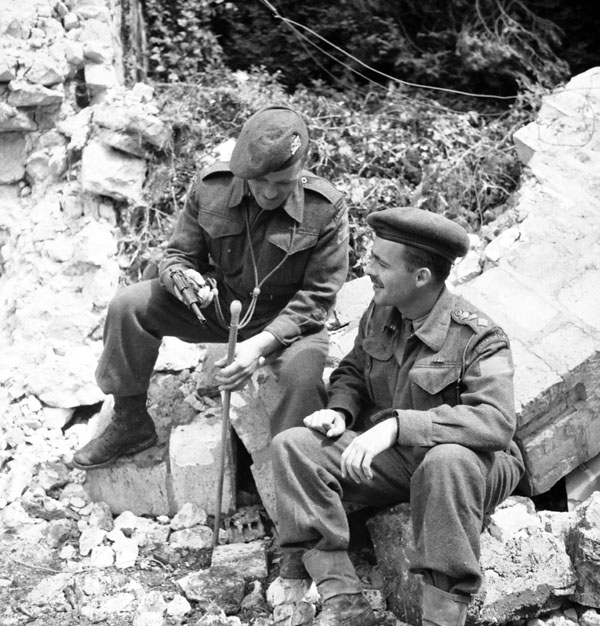 Regimental Sergeant-Major Antonio Lamontagne and Captain Pierre LaBrecque, both of Le Régiment de la Chaudière, sitting outside a church destroyed by shellfire, Carpiquet, France, 6 July 1944.