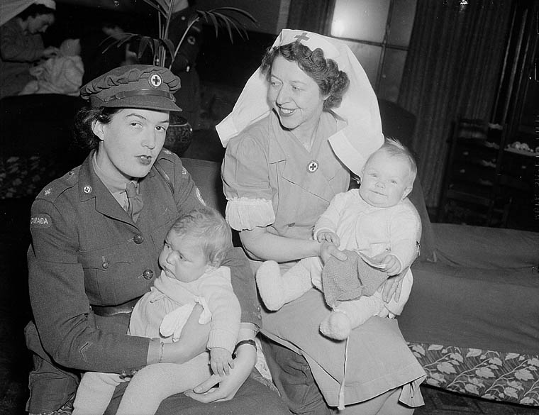 Miss Dilys Owen and Mrs. Roley Harris of the Canadian Red Cross looking after the babies of war brides en route to Canada, No.2 Maple Leaf Club, London, England, 4 December 1944.