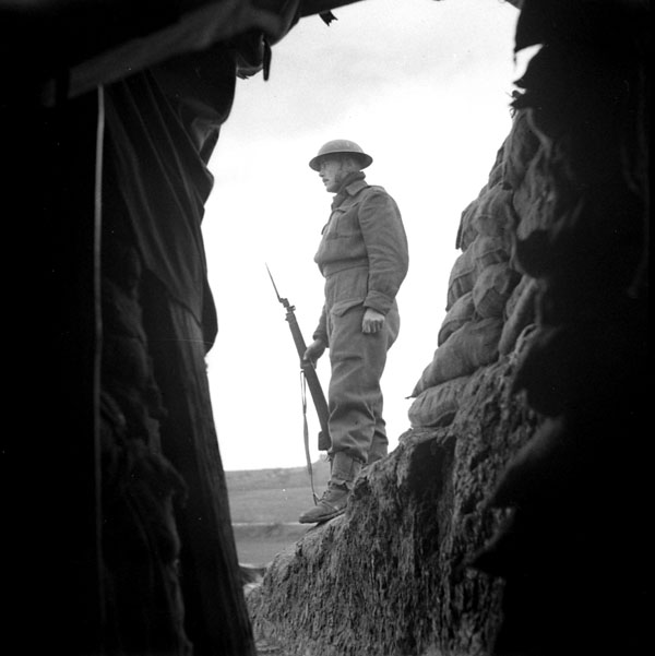 Gunner Douglas Hat on guard outside the Battery Command Post of the 17th Field Regiment, Royal Canadian Artillery (R.C.A.), Castel Frentano, Italy, 10 February 1944.