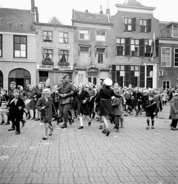Dutch children dressed in orange paper hats and ribbons to celebrate the 2nd Canadian Infantry Division's liberation of Goes, Netherlands, 30 October 1944.